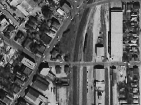 The Acme and adjacent structures appear on the upper left off Austin Street, 1963; across the street is the abandoned railway [https.//historicaerials.com]